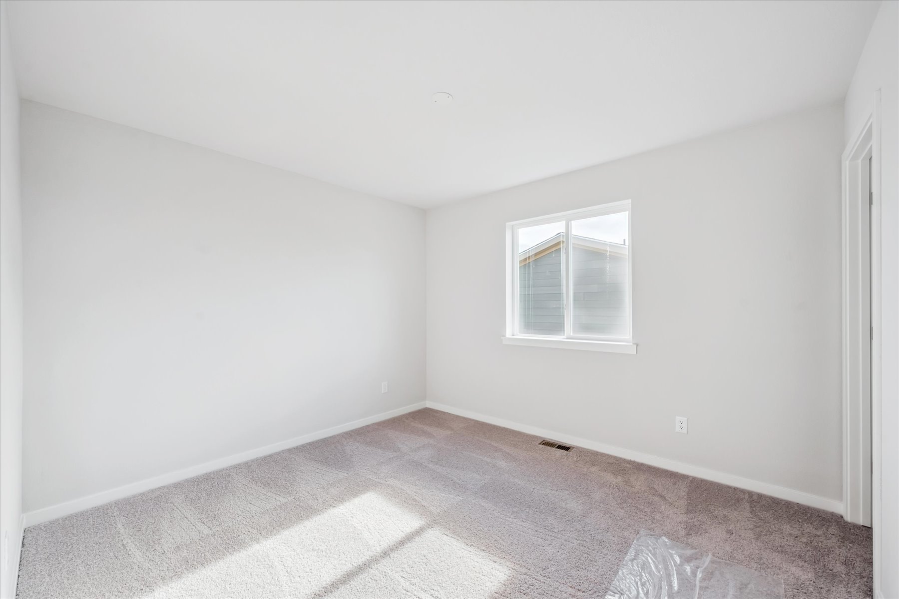 A room with a window and a rug.