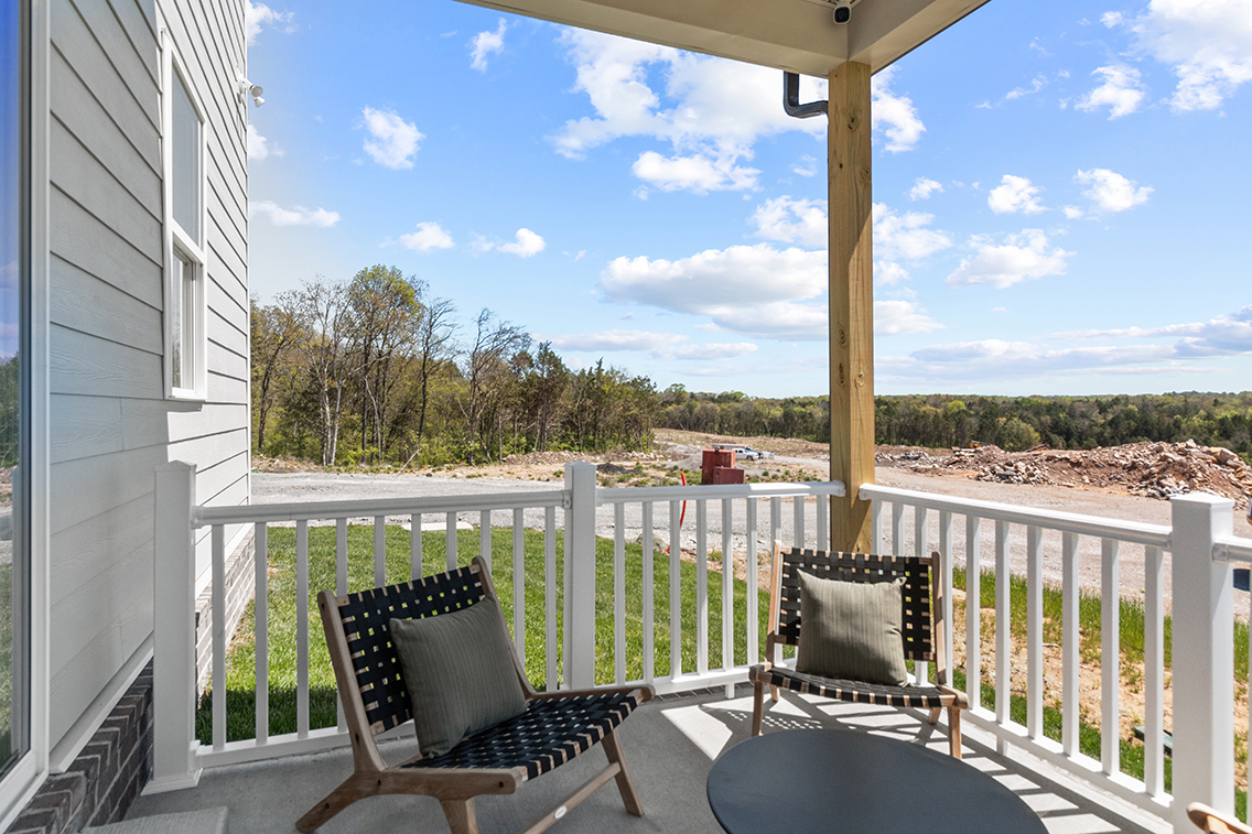 A deck with chairs and a table on it by a building.
