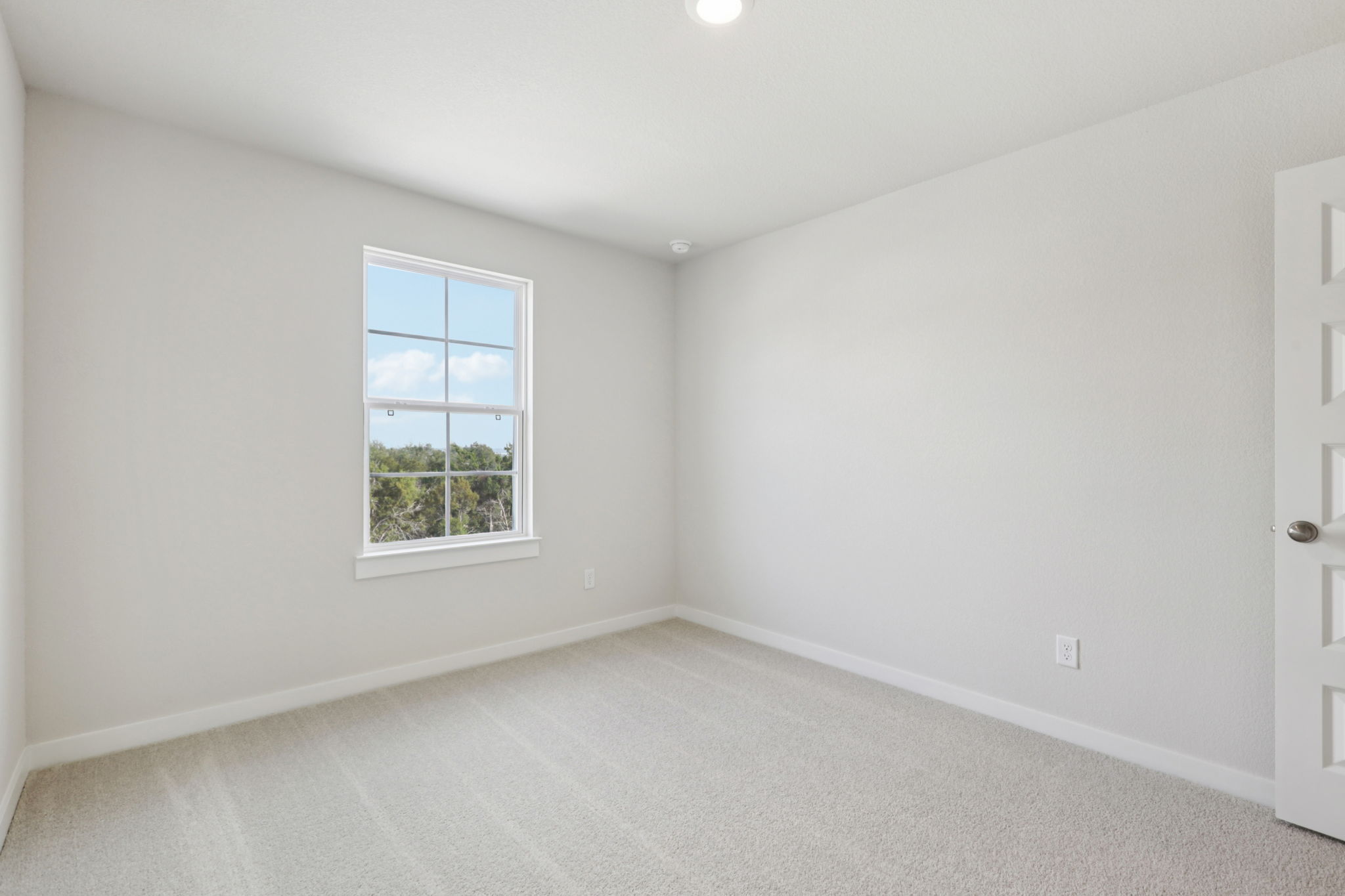 A room with a window and a white wall.