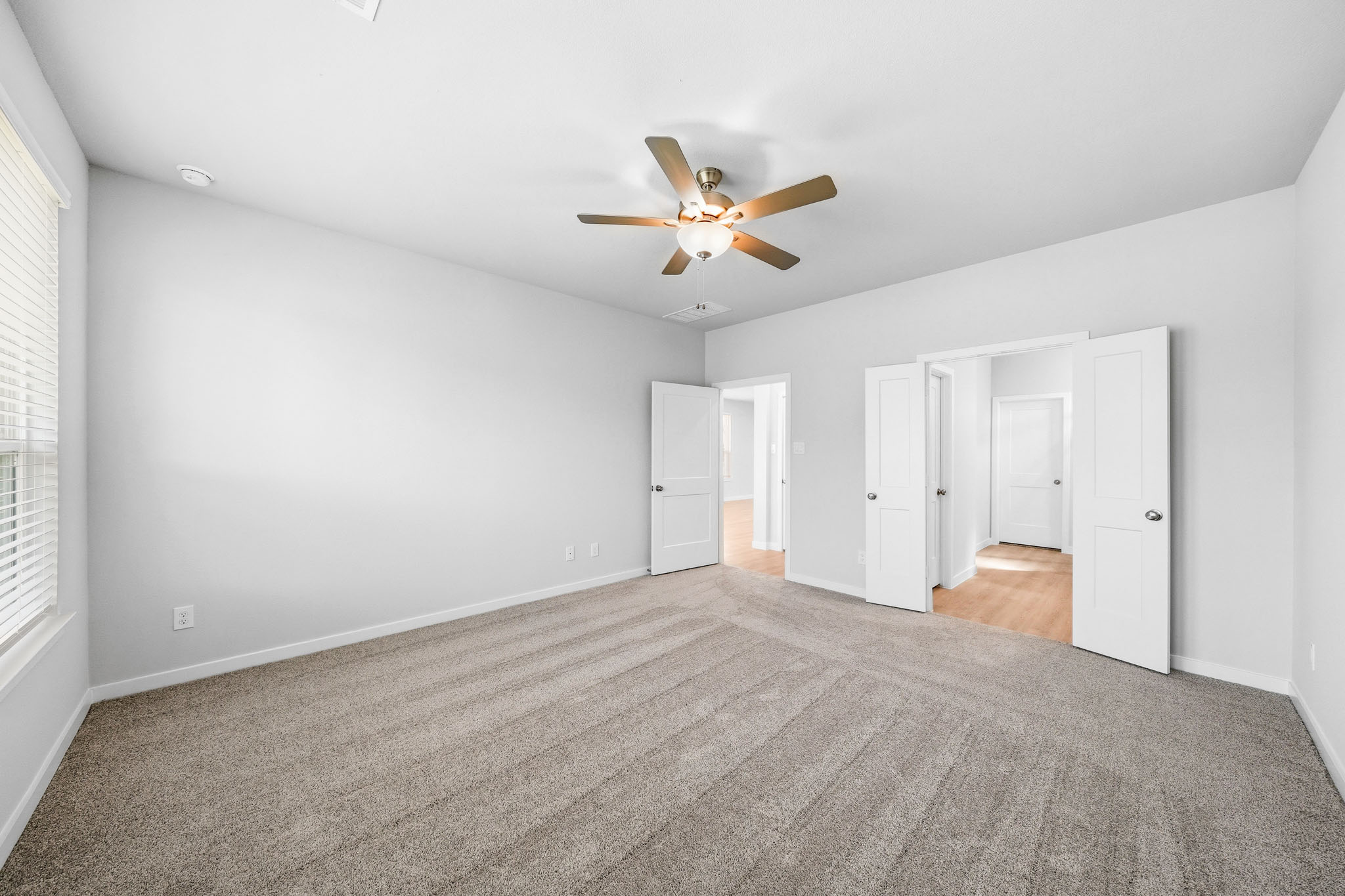 A room with a ceiling fan and white walls.