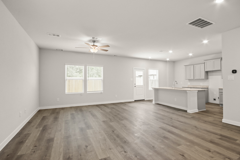 A large empty room with a wood floor and a ceiling fan.