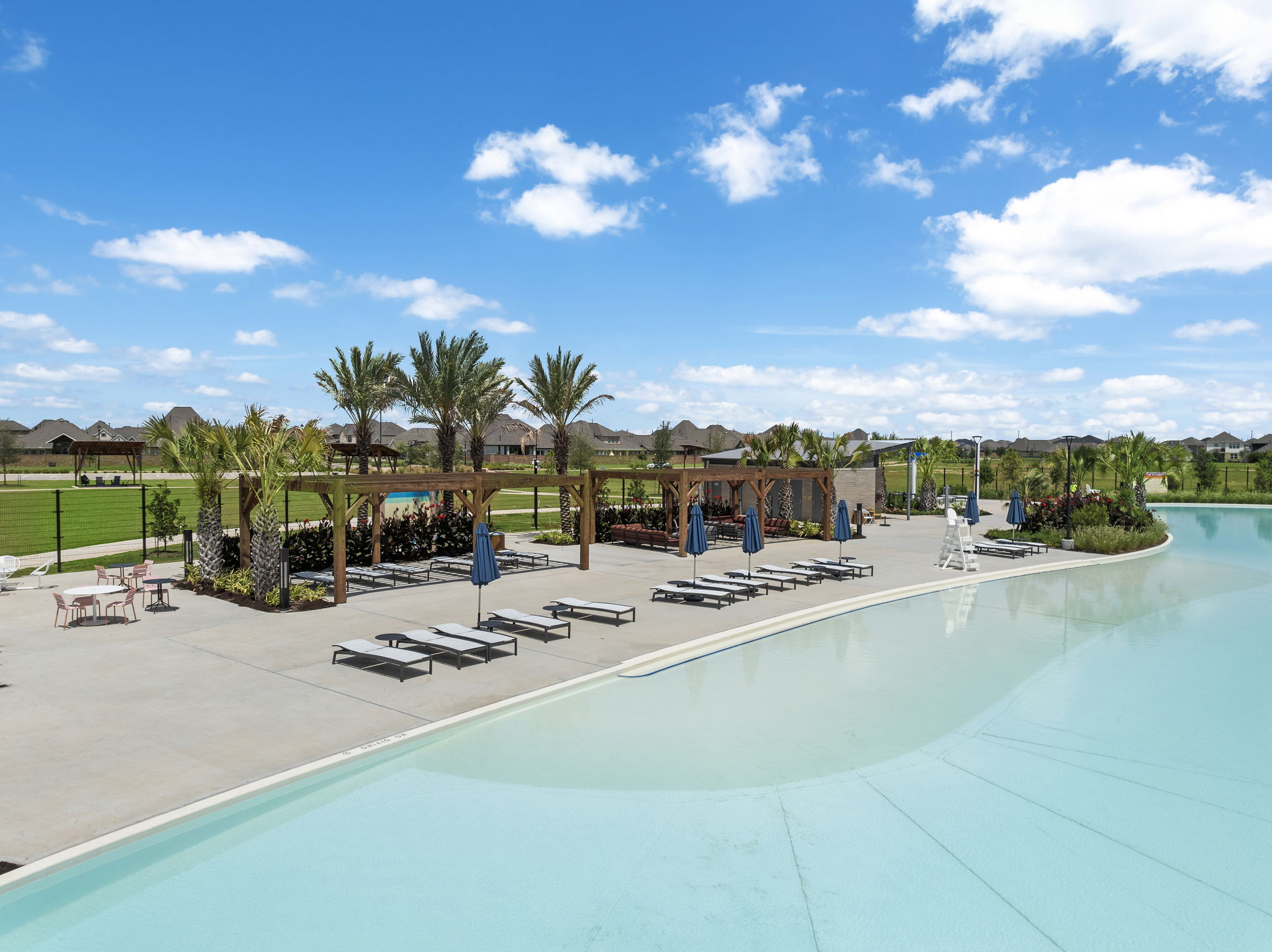 A swimming pool with lounge chairs and trees in the background.