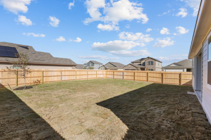 A fenced in yard with houses in the background.